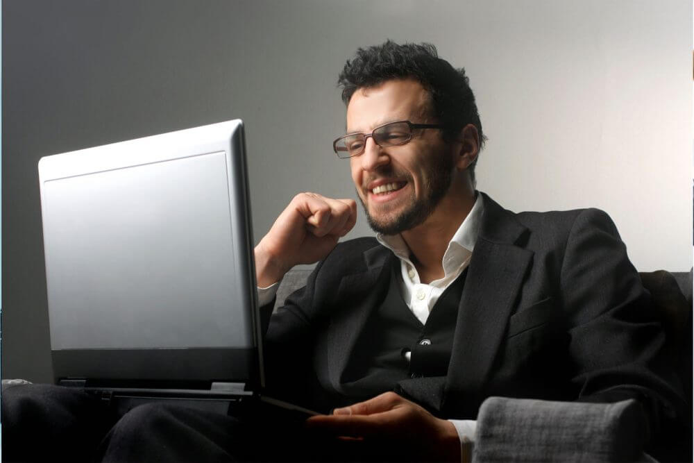 a man smiling in front of a laptop